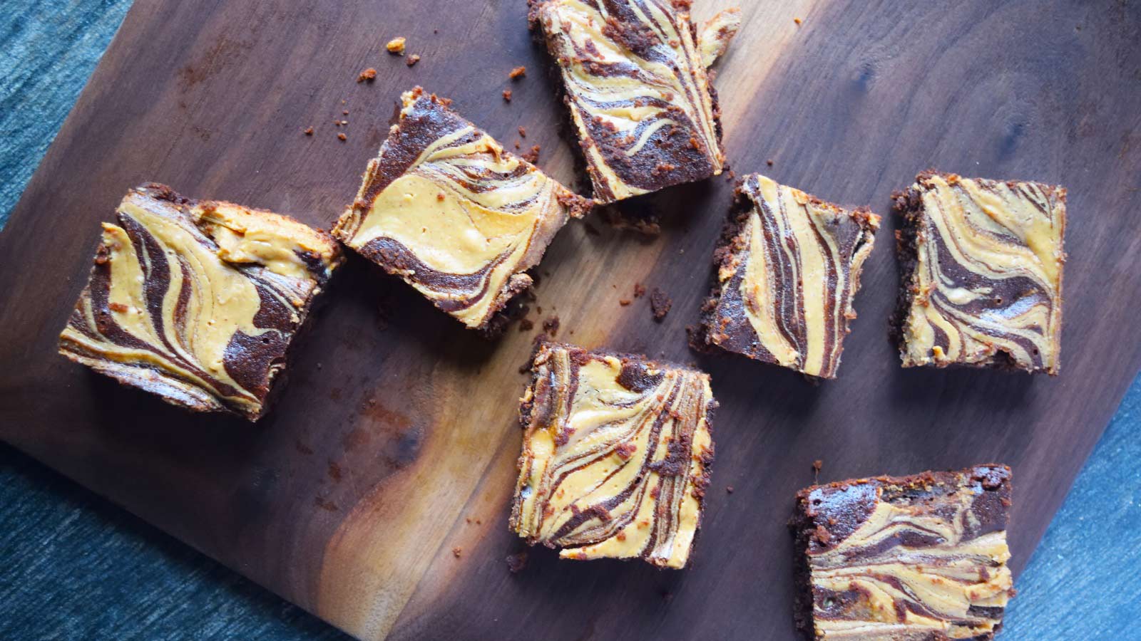 An overhead view of of some cut Peanut Butter Swirl Brownies laying on a wood cutting board.