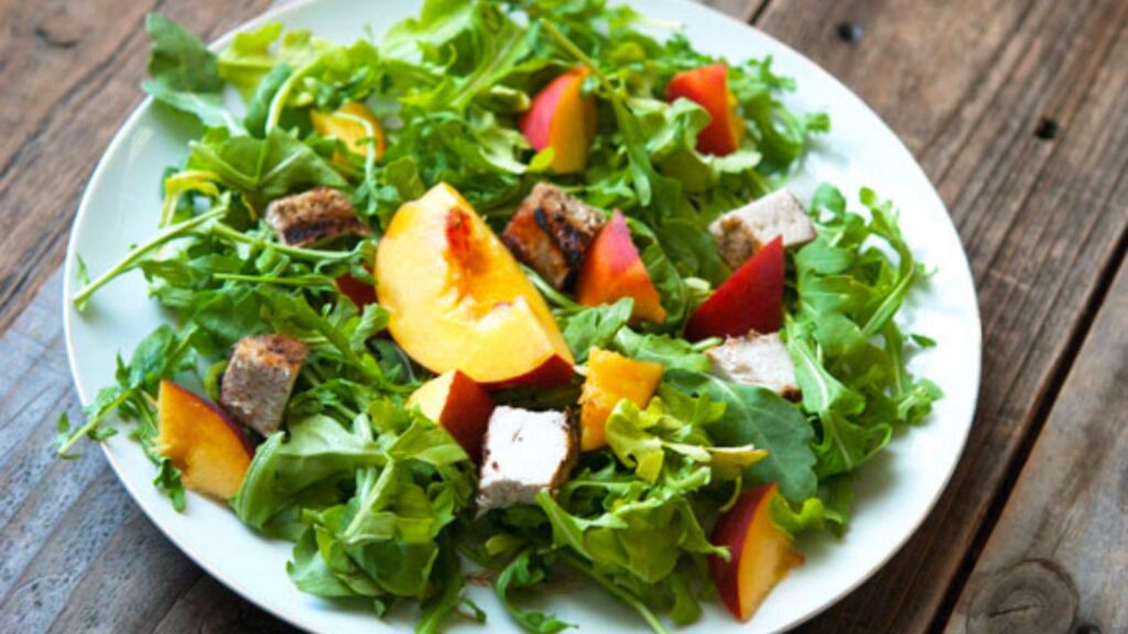 Pork, Peach & Arugula Salad With Peach Vinaigrette on a white plate