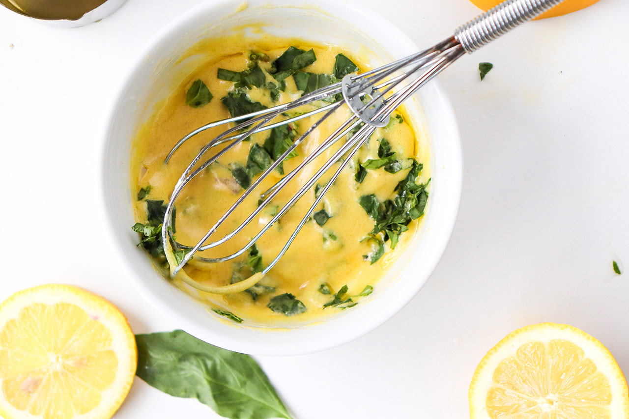 Orzo salad dressing ingredients whisked together in a small, white mixing bowl.