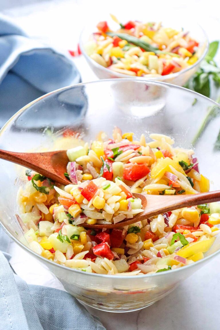 Two glass bowls filled with Rainbow Orzo Salad on a white tabletop.