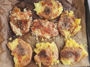 Roasted and smashed red potatoes on a parchment-lined baking pan.