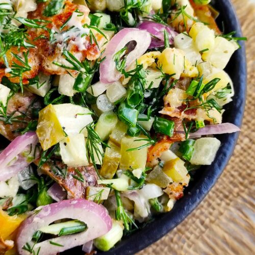 An overhead closeup of a black bowl filled with Red Potato Salad.