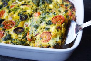 A metal spatula starting to lift out a serving of spinach quiche.