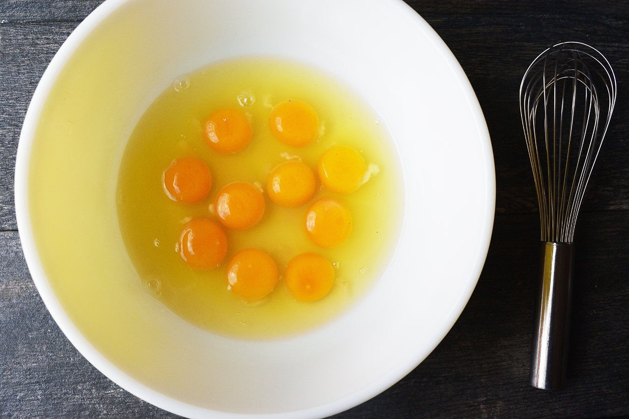 Ten eggs cracked into a large mixing bowl.