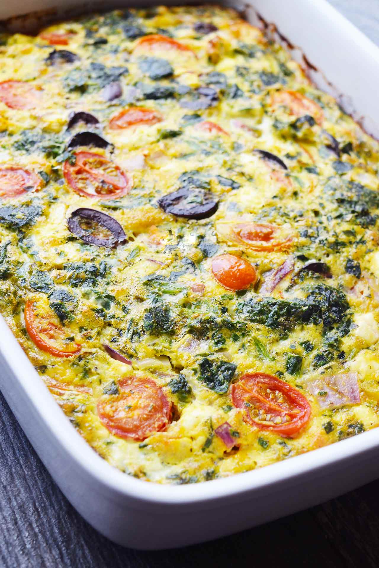 A front view of a white casserole dish filled with spinach quiche.