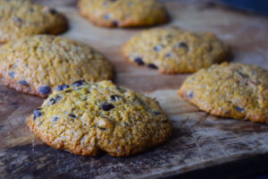 A closeup of Superfood Chocolate Chip Cookies cooling on a wood cutting board.