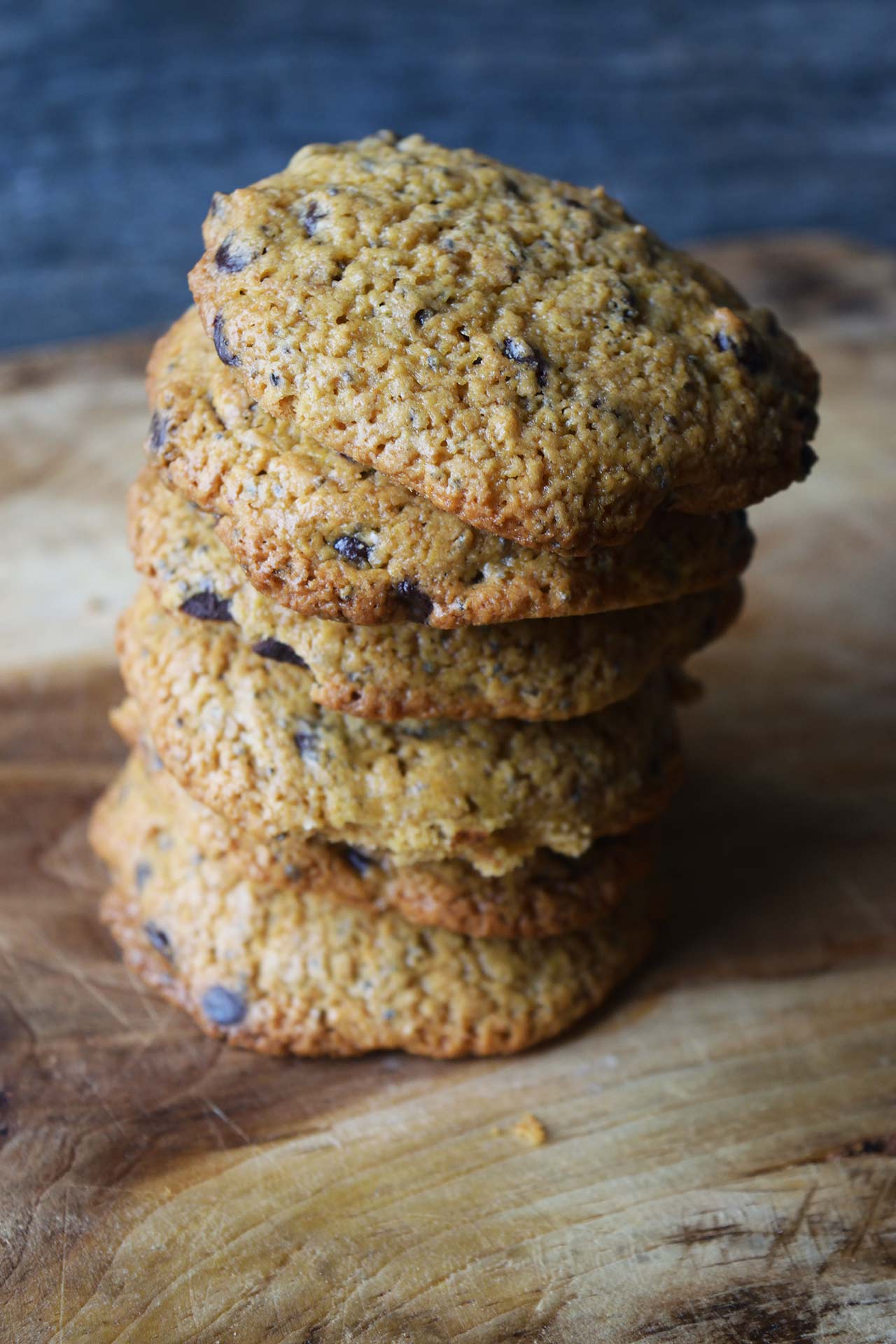 A stack of Superfood Chocolate Chip Cookies tilting to the right on a wood cutting board.