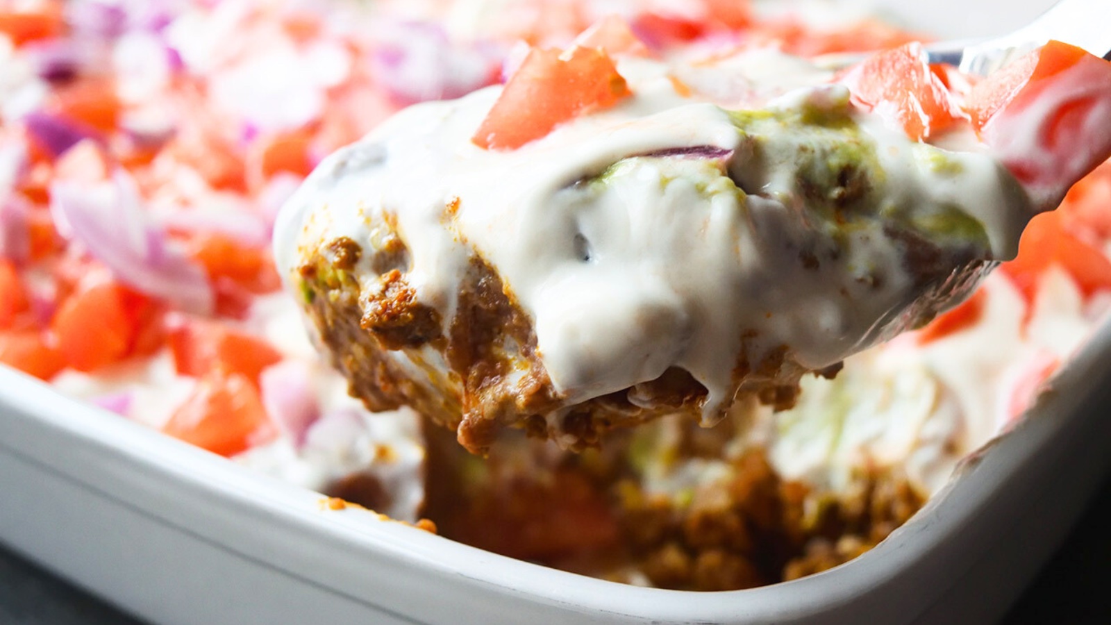 A spoonful of Taco Salad Casserole from a white casserole dish.