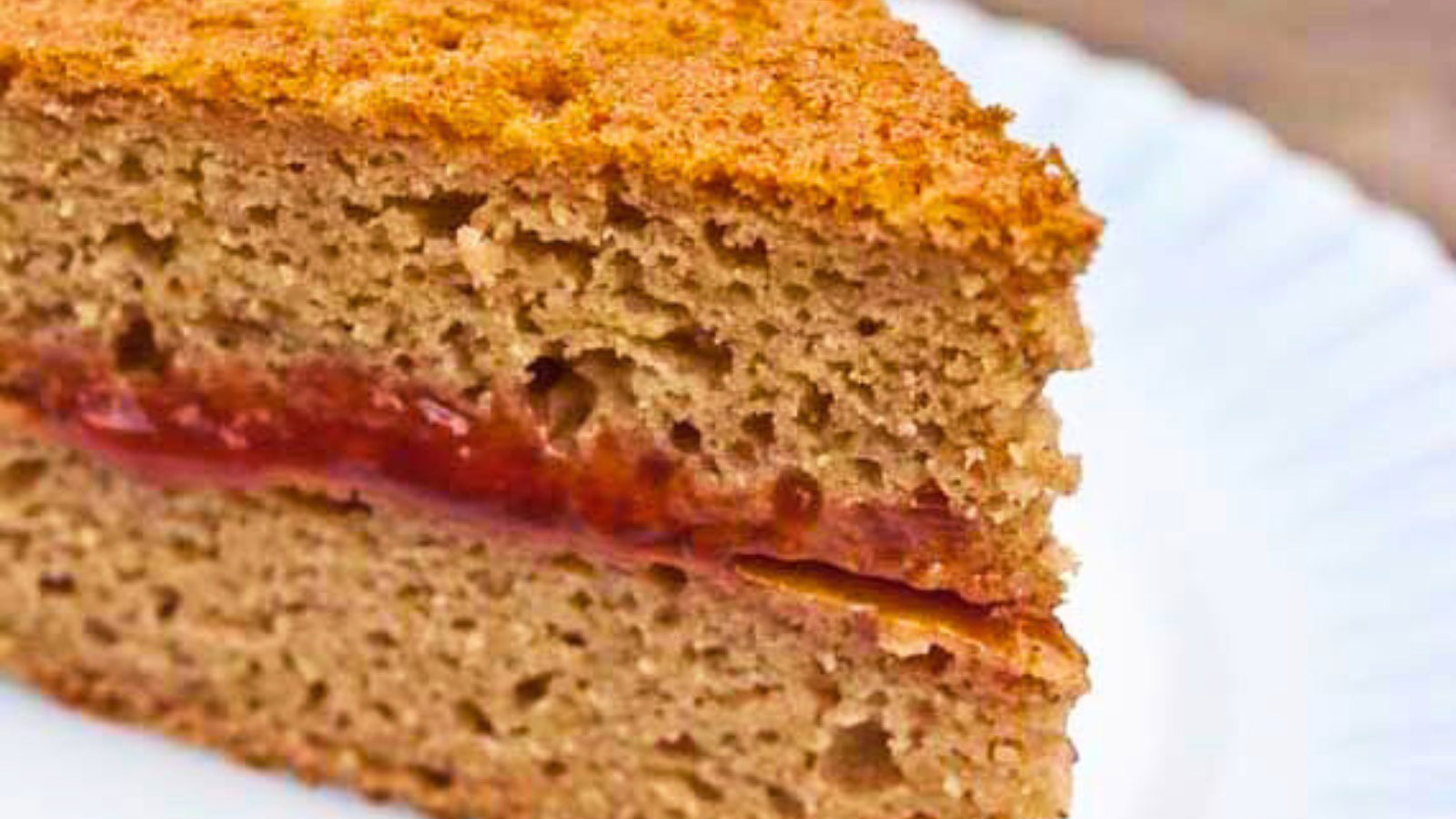 An up close view of a slice of whole wheat cake on a white plate.