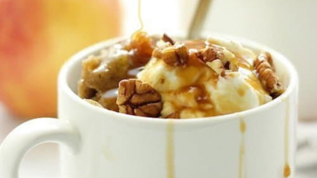 A closeup view of a white mug filled with apple spice protein mug cake.