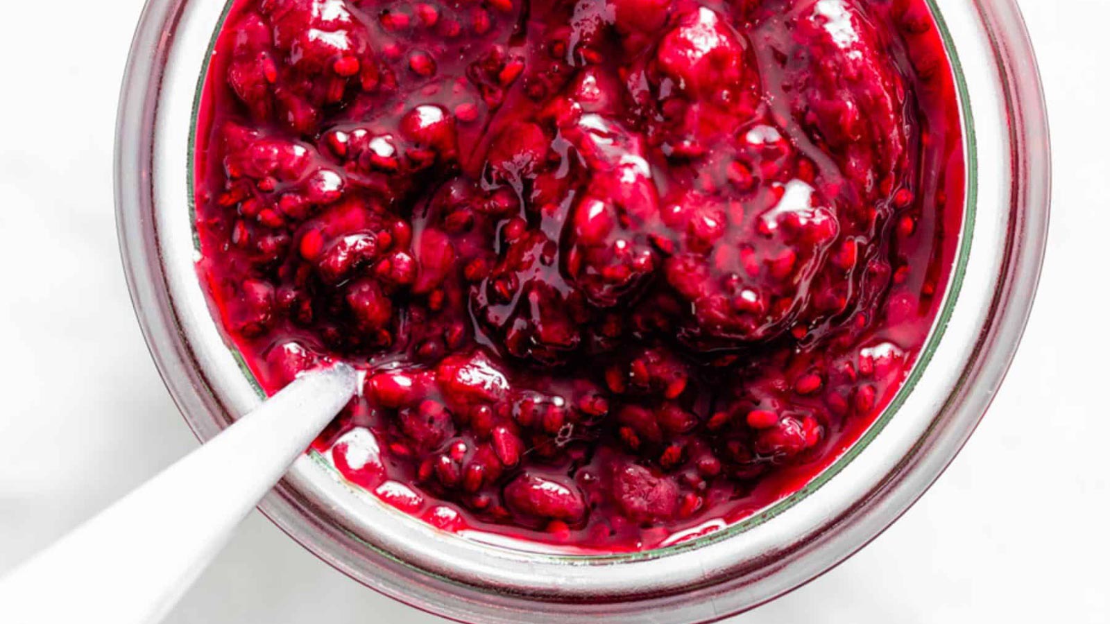 An overhead view of an open jar with a spoon, filled with Instant Pot blackberry chia jam.