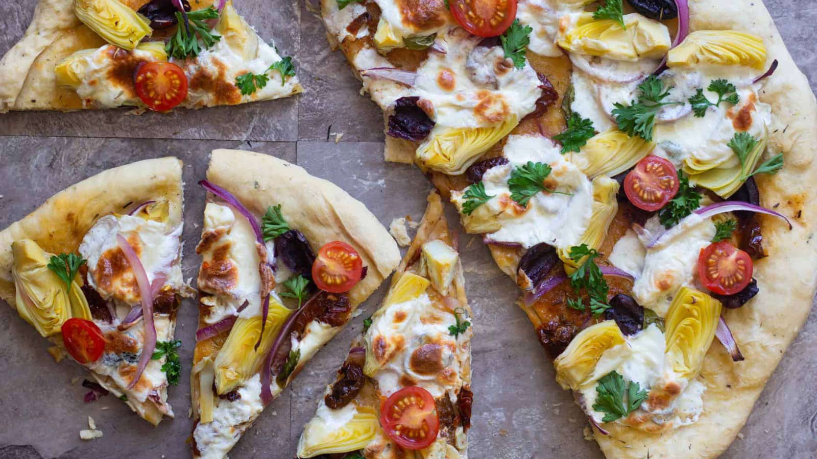 An overhead view of Mediterranean Pizza cut into slices.