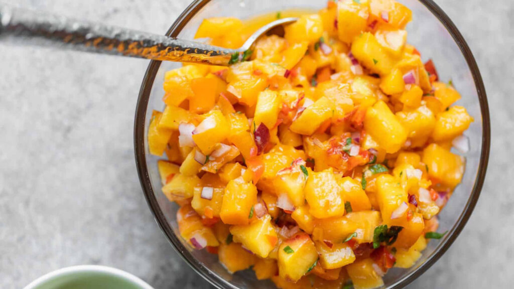 An overhead view of a glass bowl filled with peach habanero salsa.