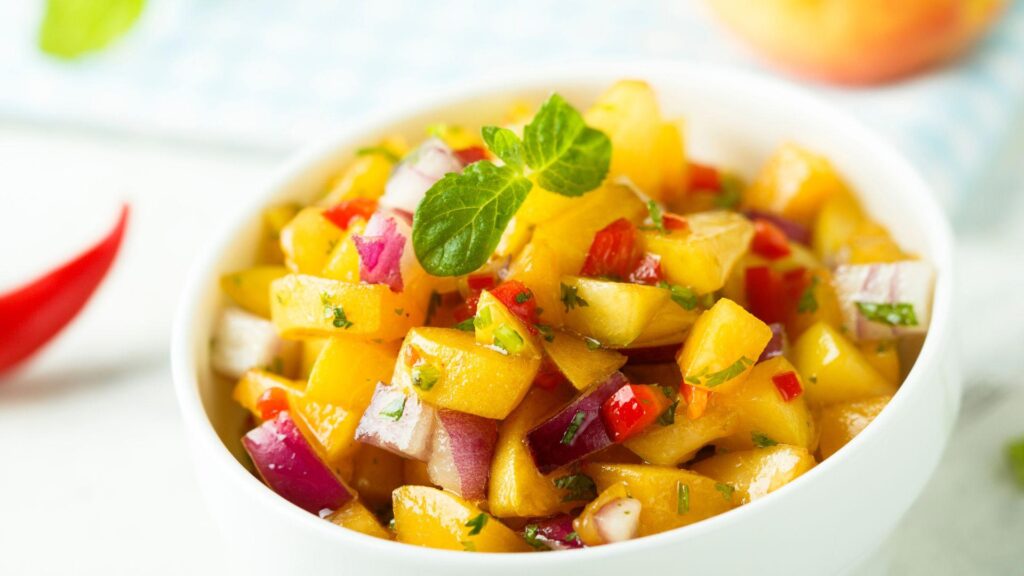 A white bowl full of spicy peach salsa.