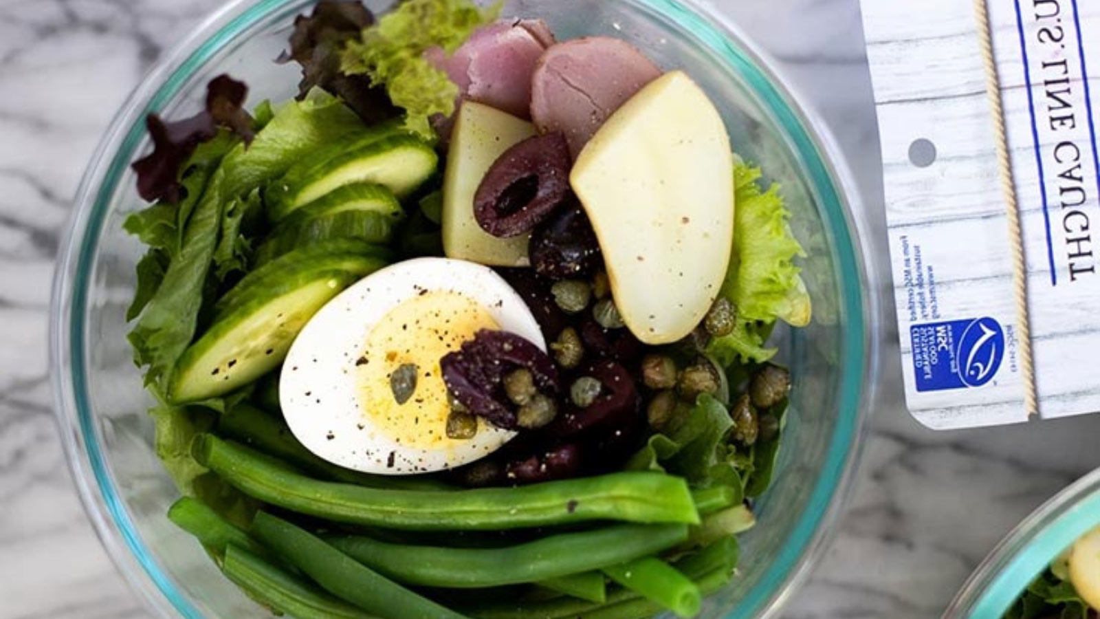 An overhead view of a glass bowl filled with tuna nicoise salad.