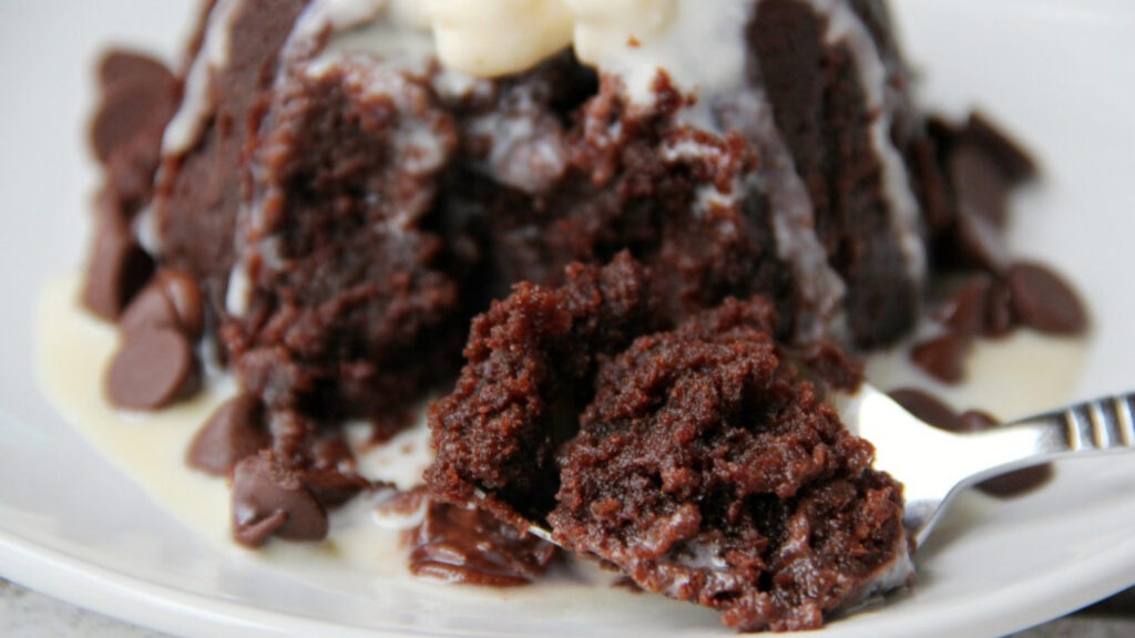 Closeup of a mug brownie on a plate with a fork.