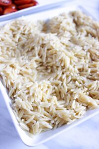 Cooked orzo on a baking sheet for cooling.