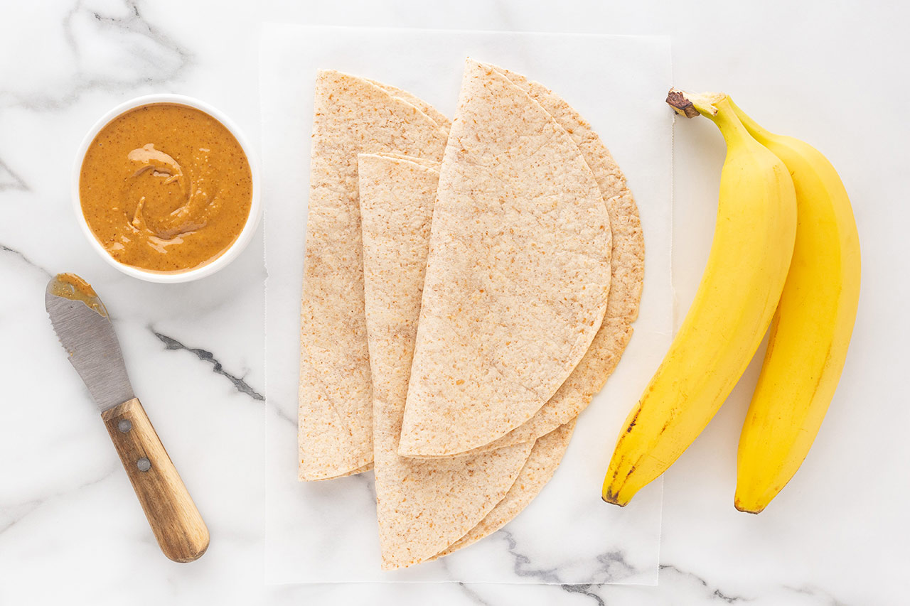 Banana Wrap recipe ingredients gathered on a white marble surface.