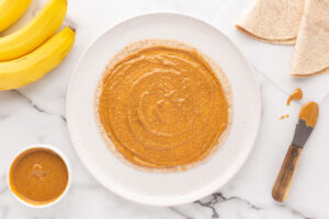 Peanut butter spread over a tortilla on a plate.