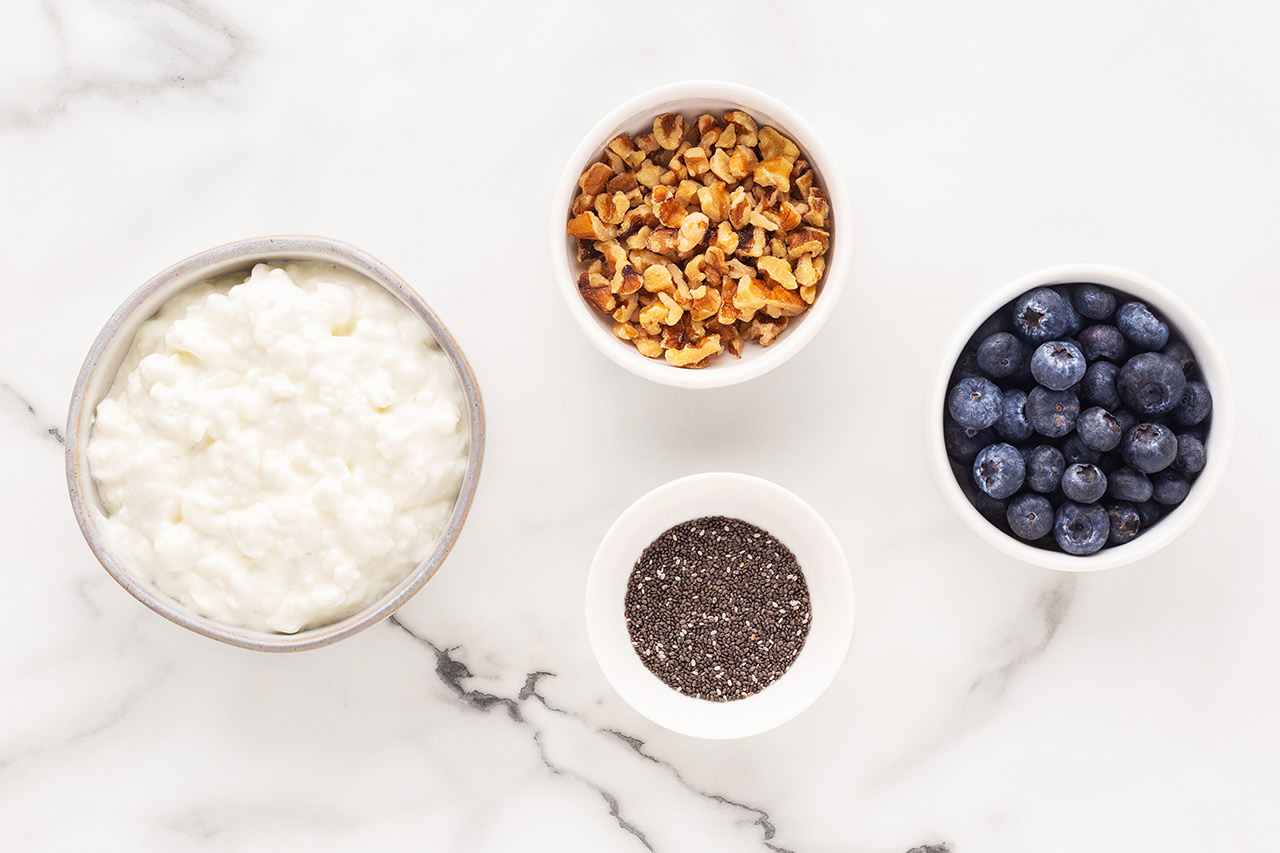Blueberry Cottage Cheese Recipe ingredients on a white marble surface.