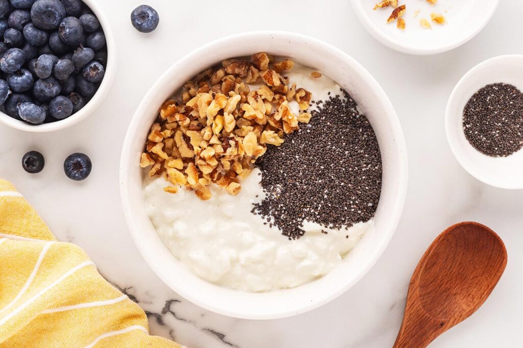 Walnuts sprinkled over cottage cheese in a white bowl.
