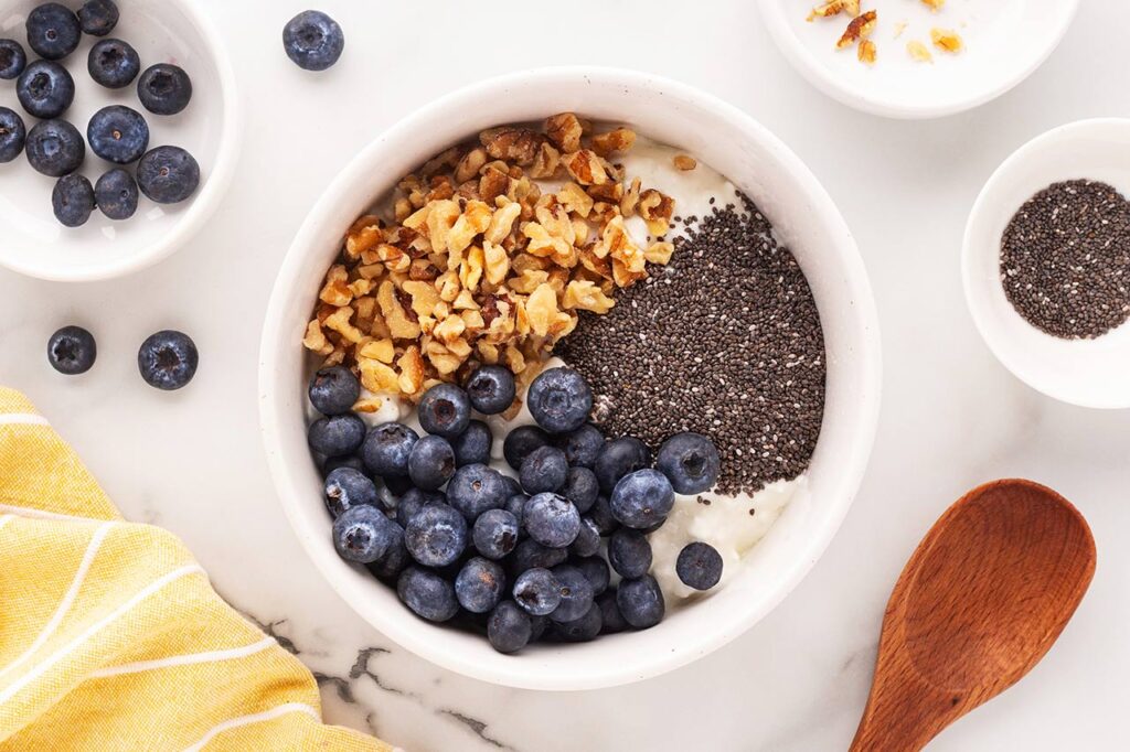 Fresh blueberries sprinkled over cottage cheese in a white bowl.