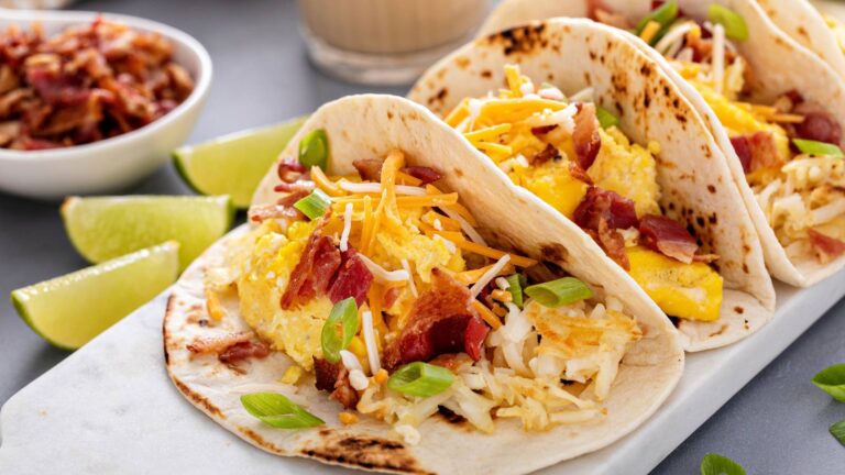 Breakfast tacos with hashbrowns, scrambled eggs and bacon topped with cheese and green onion