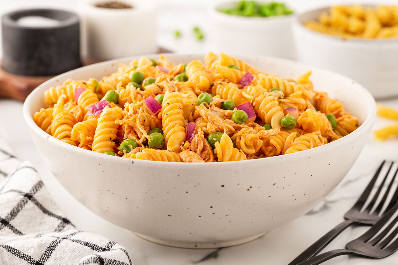 A side view of a white bowl filled with Buffalo Chicken Pasta Salad.