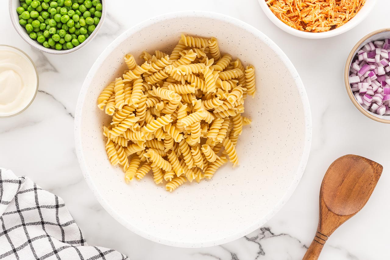 Cooked rotini pasta in a mixing bowl.