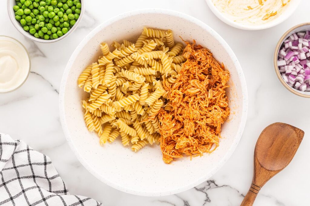 Shreeded buffalo chicken in a bowl with pasta.