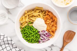 Mayo added to Buffalo Chicken Pasta Salad ingredients in a mixing bowl.