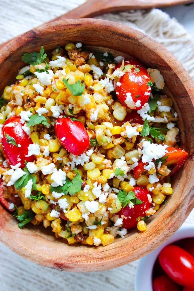 An overhead view of a wood bowl filled with Roasted Corn Salad.
