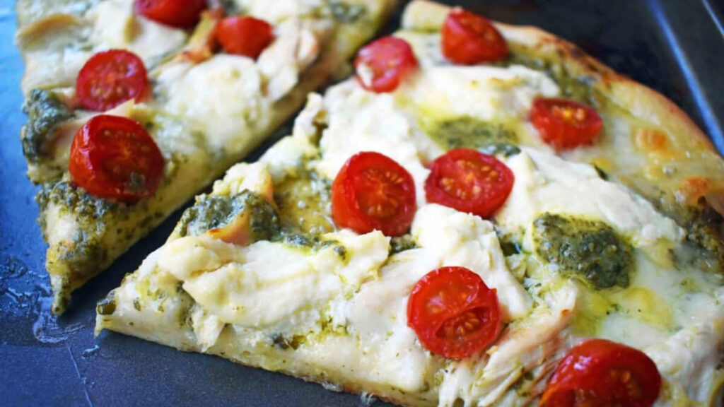 A closeup of a few slices of chicken pesto pizza.