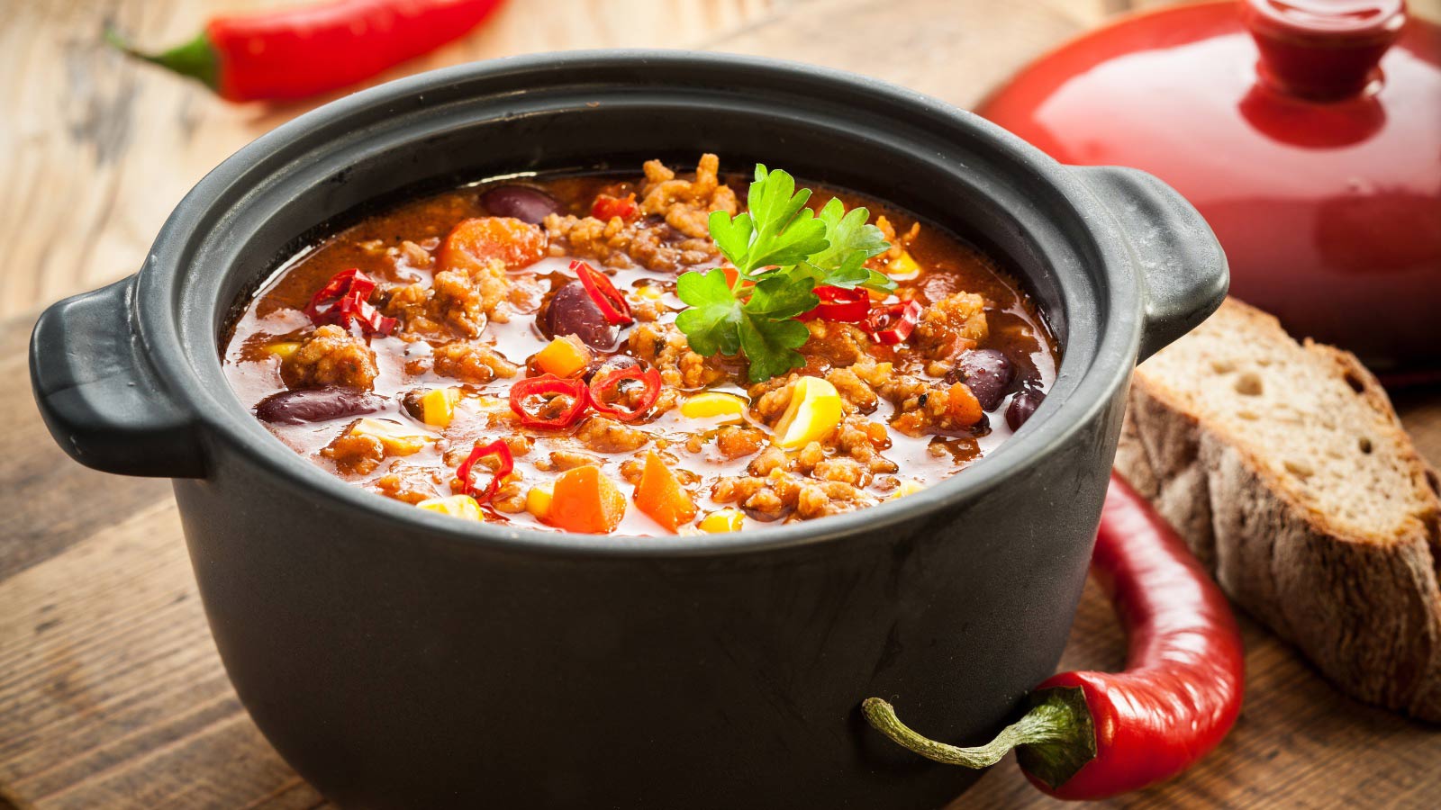 Tasty spicy chili con carne in a black pot.