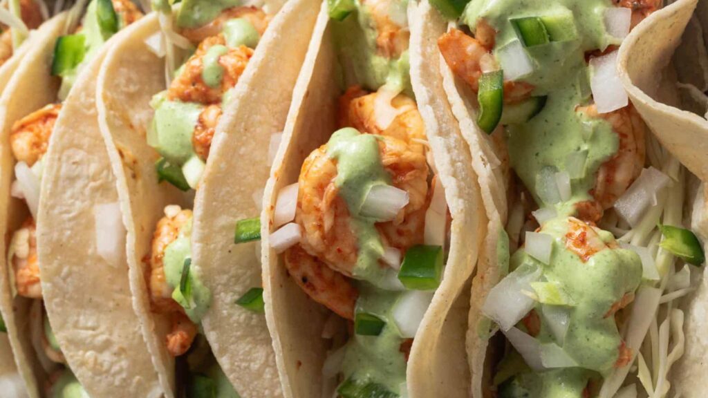 A closeup of a row of chili lime shrimp tacos.
