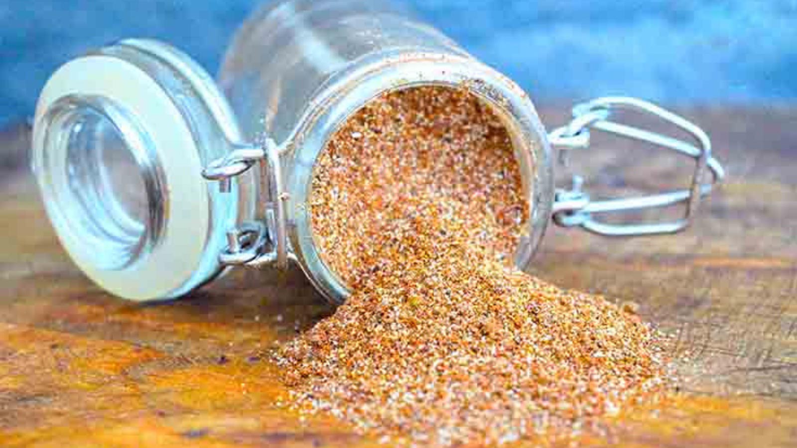 Chili Spice in an open jar, tipped over onto a wooden surface.
