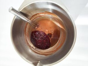 Raspberry fruit spread added to the mixing bowl of batter ingredients.