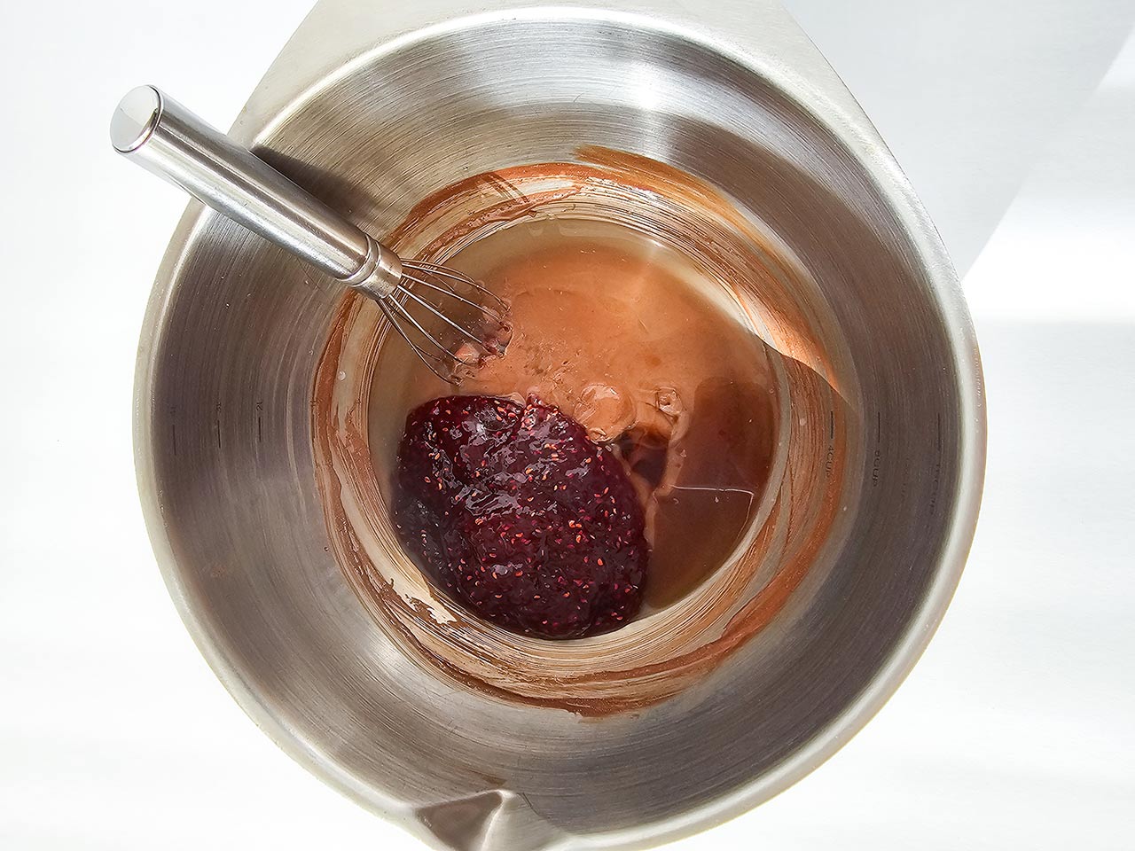 Raspberry fruit spread added to the mixing bowl of batter ingredients.