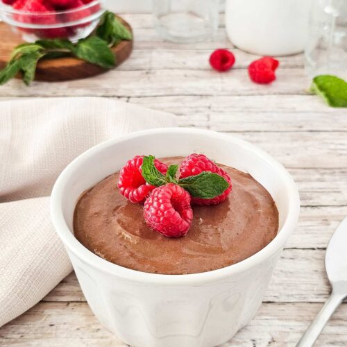 A side view of a white bowl filled with raspberry chocolate mousse.