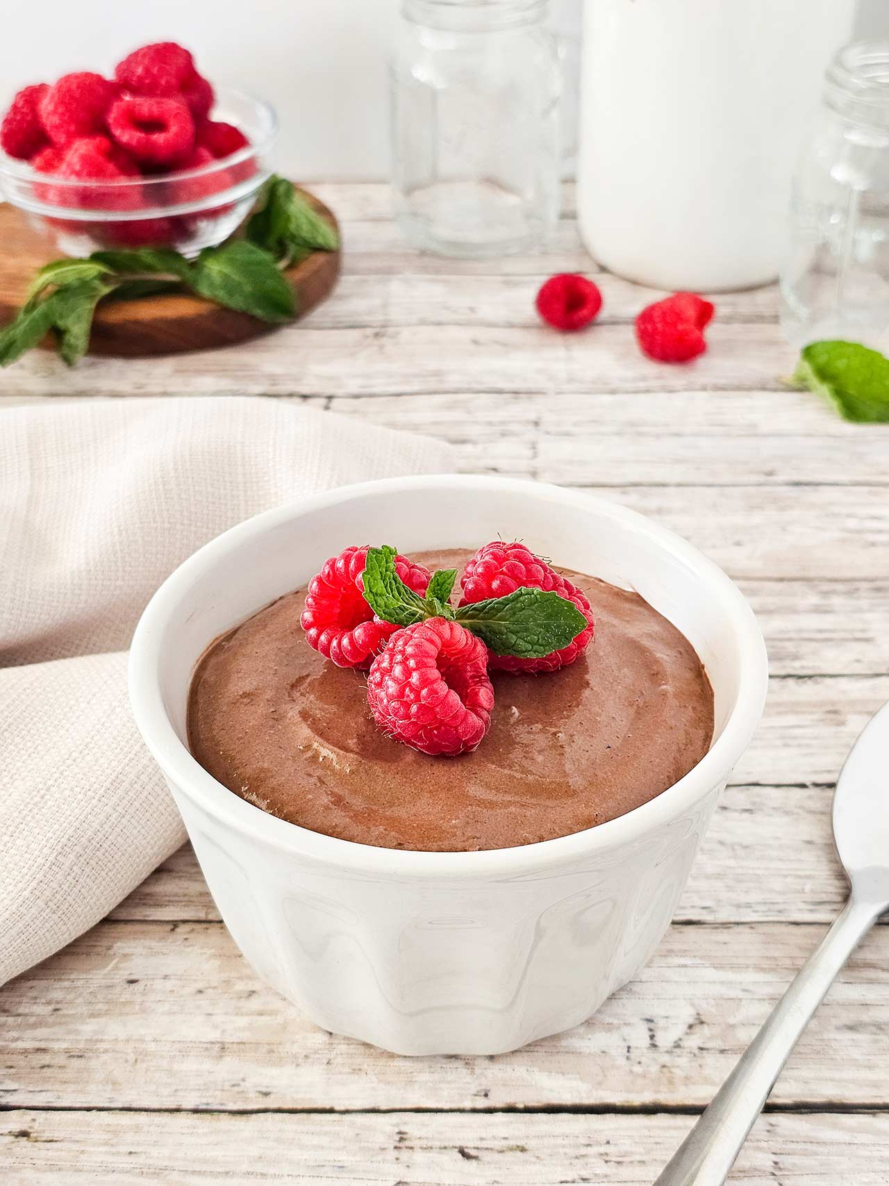A side view of a white bowl filled with raspberry chocolate mousse.
