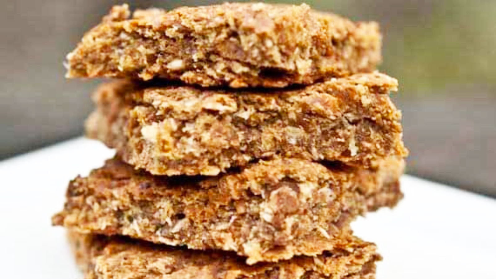 A closeup of a stack of Coconut Lime Oat Bars on a white plate.
