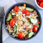 Overhead view of a black bowl filled with Greek Orzo Salad.