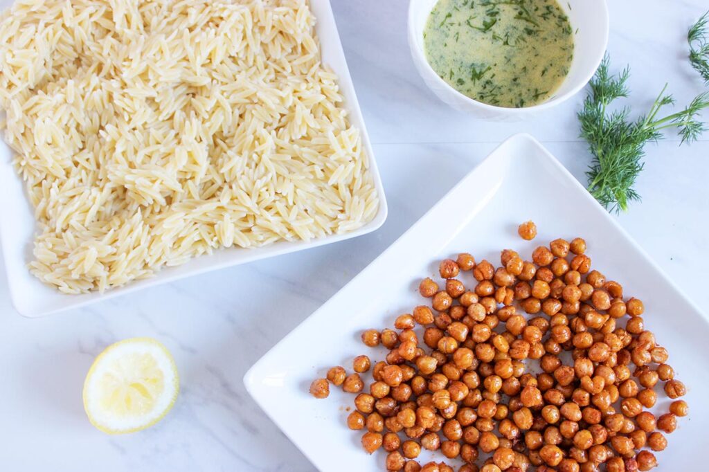 Seasoned chickpeas on a platter and orzo cooling on another platter.