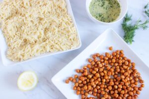 Seasoned chickpeas on a platter and orzo cooling on another platter.