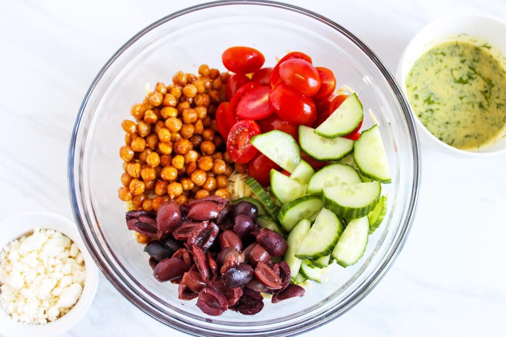 Greek Orzo Salad ingredients in a large mixing bowl.