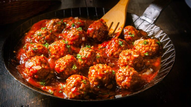 Delicious meatballs made from ground beef in a spicy tomato sauce served in a skillet or old metal pan.