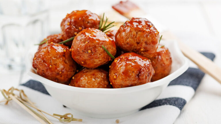 Ground Turkey Meatballs with glaze on white and blue stripped dish towel on a white surface.