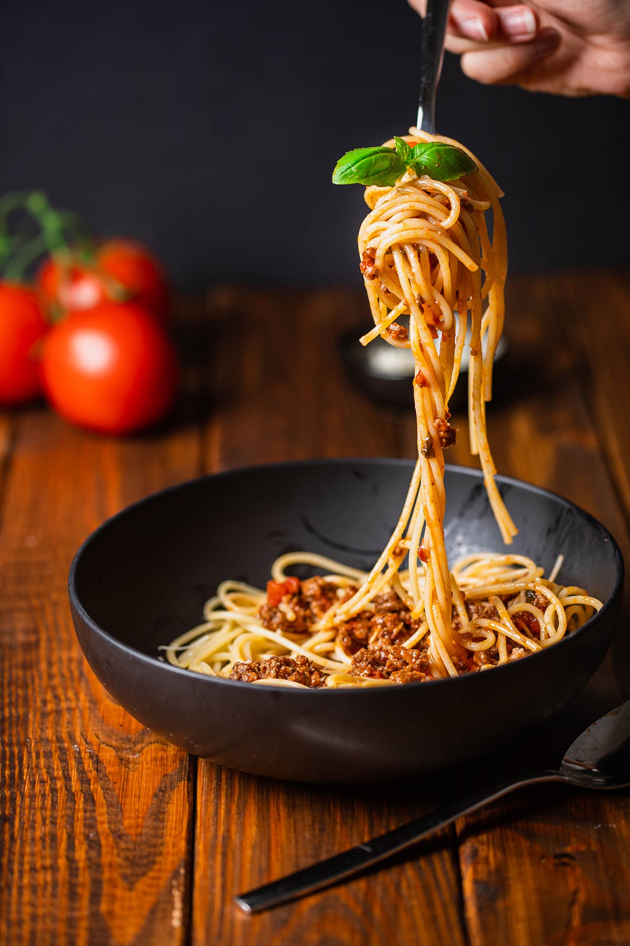 A fork lifts a twist of ground turkey spaghetti out of a black bowl.