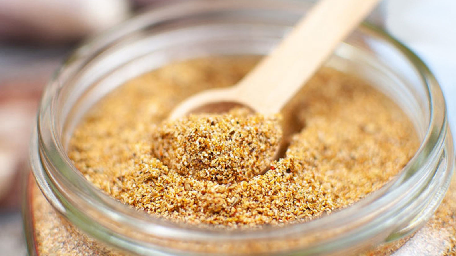 The finished Homemade Fajita Seasoning in an open jar with a small scoop sitting inside.