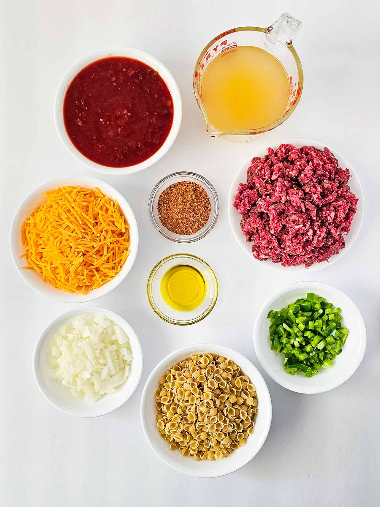 Ingredients for Instant Pot Taco Casserole in individual bowls on a white surface. Overhead focus.